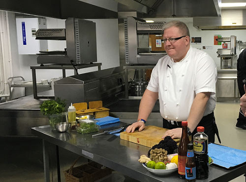 Paul Askew doing a Masterclass on cooking wearing a white t-shirt