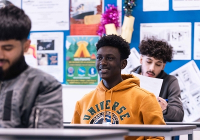 Two Part Time ESOL Students Pointing At World Map In Classroom