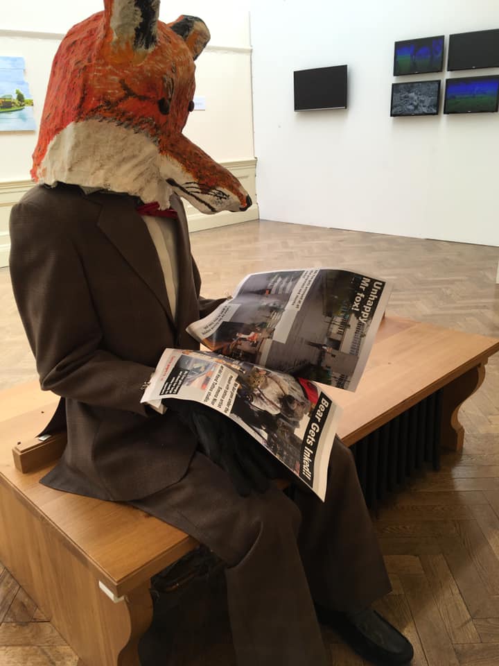 Fine Art Degree Show art piece of a man dressed in a brown suit, a red tie and a large fox mask